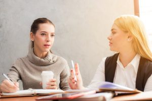 Two women working and talking to one another