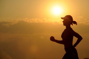 Woman running in front of a sunset