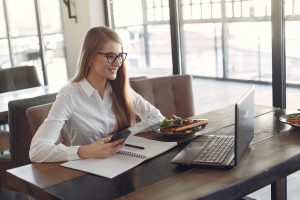 young cheerful businesswoman using smartphone and laptop