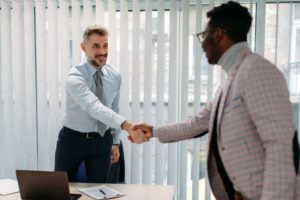 A Caucasian man shaking hands with an African man in an office