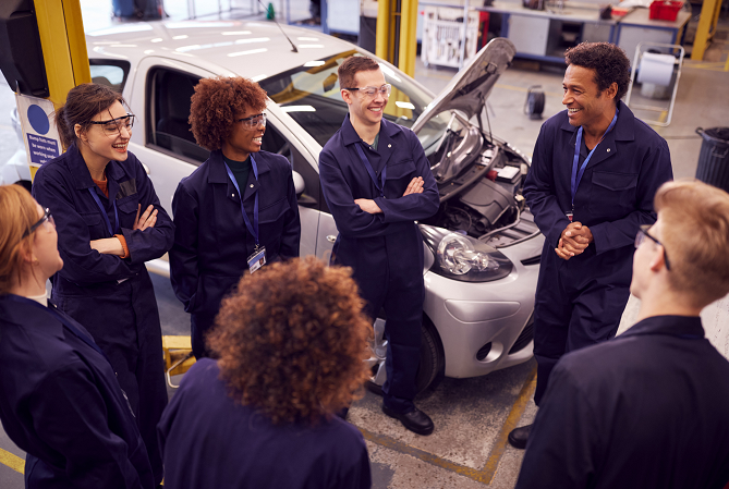 Apprentice mechanics listening to mentor