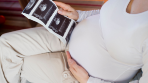 Pregnant woman holding scan photographs