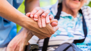 Carer holding hands with elderly person
