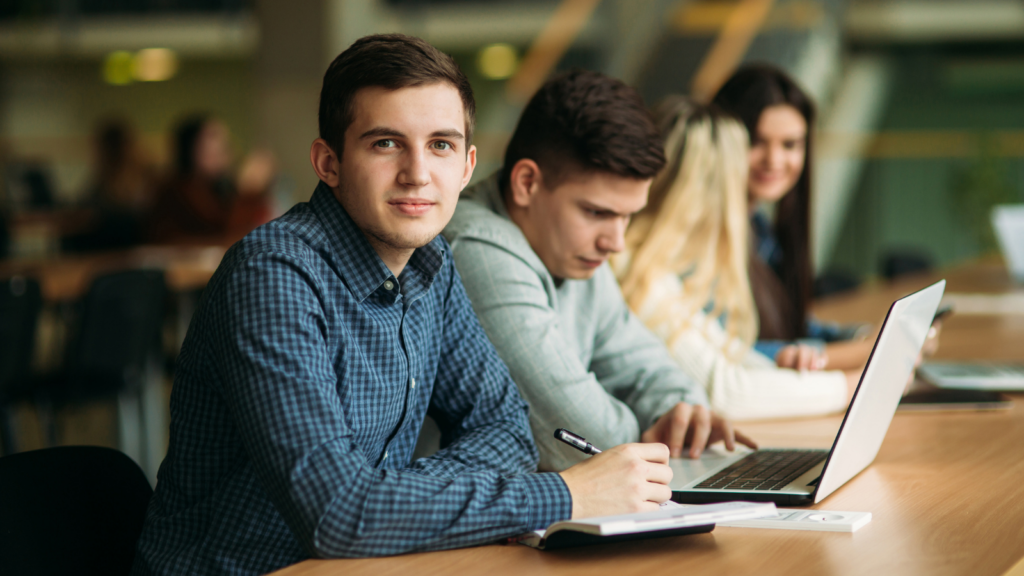 Student looking towards the camera surrounded by other students