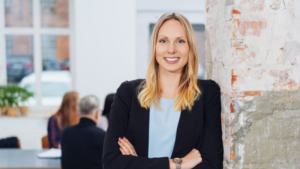 Professional women leaning against wall with arms crossed