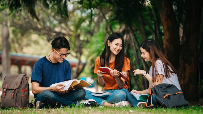 University students sat together on grass studying