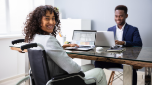 Women in wheelchair sat at desk opposite her colleague