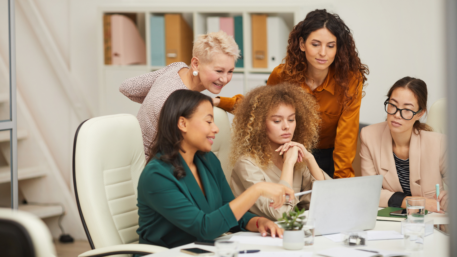 Group of colleagues collaborating together, looking at laptop screen