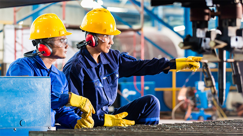 Two factory workers pointing towards something