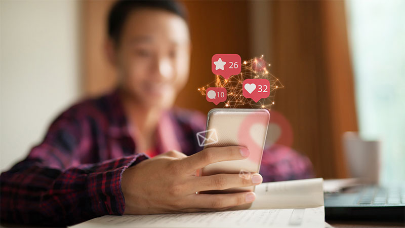 Person on phone with likes and comment numbers displayed
