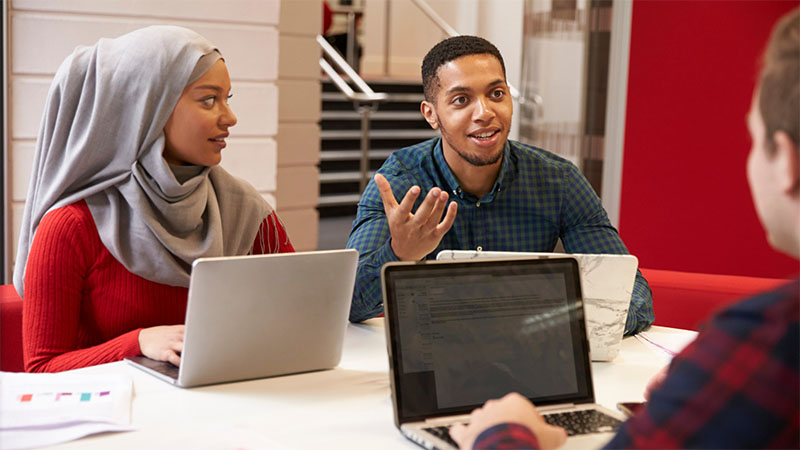 Students sat with laptops speaking to eachother