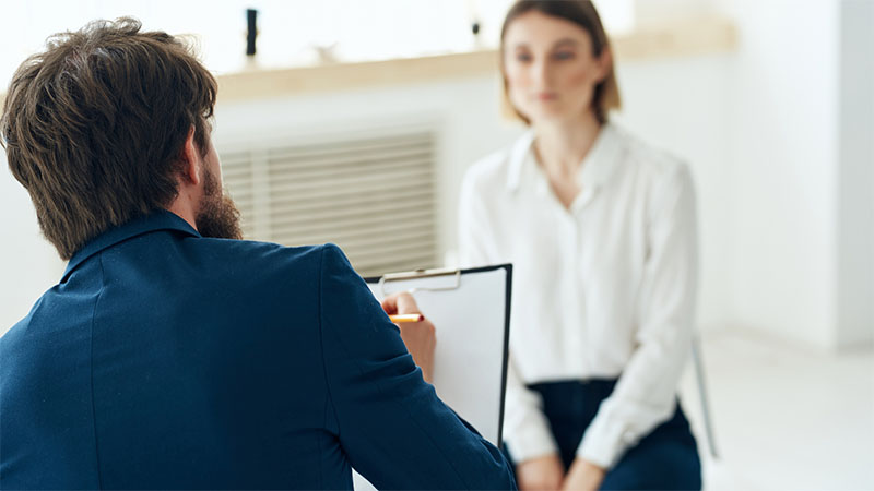 Interviewer taking notes on clipboard during interview