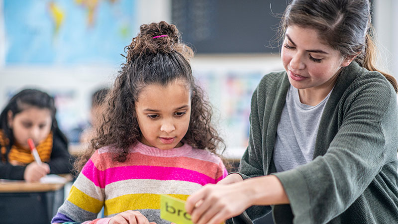 Teacher helping younger student with task